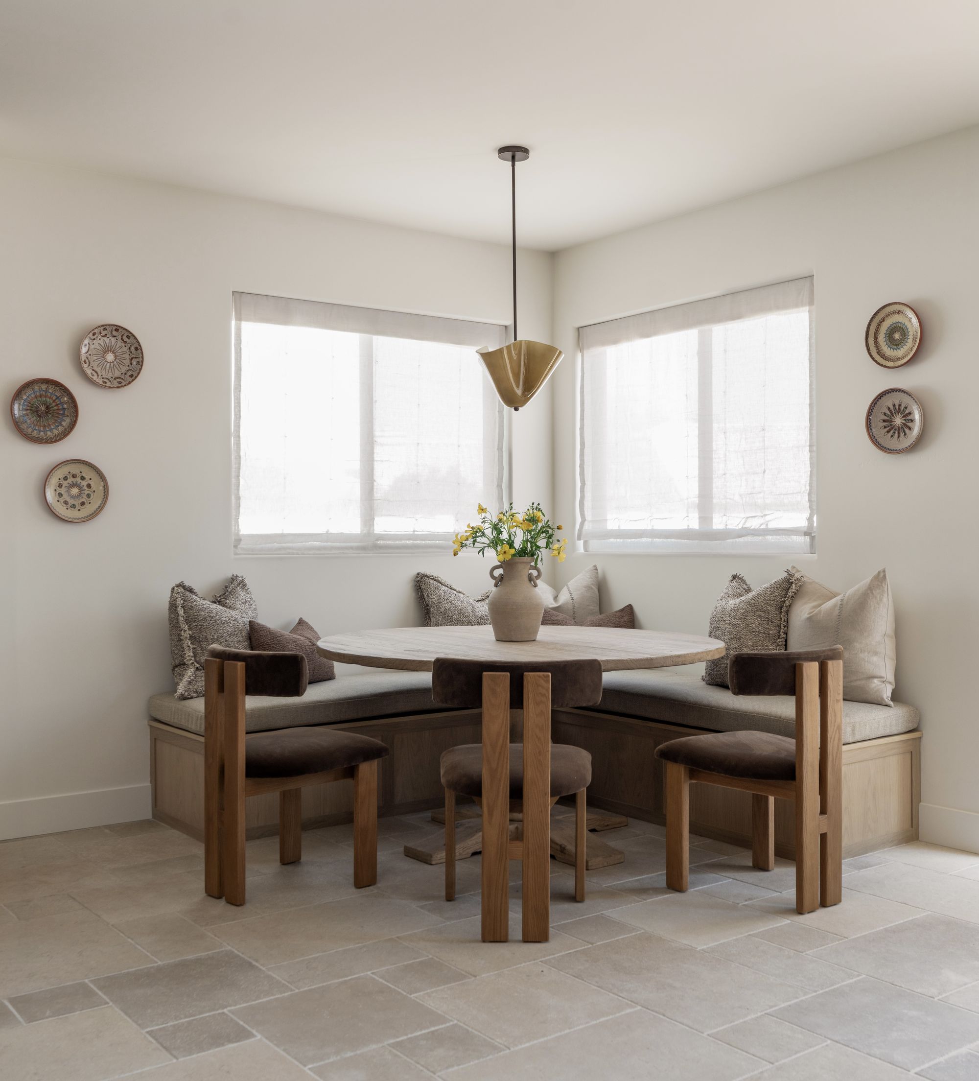 A calm, sunlit breakfast nook with a round oak table and banquette seating, made for unhurried family conversation