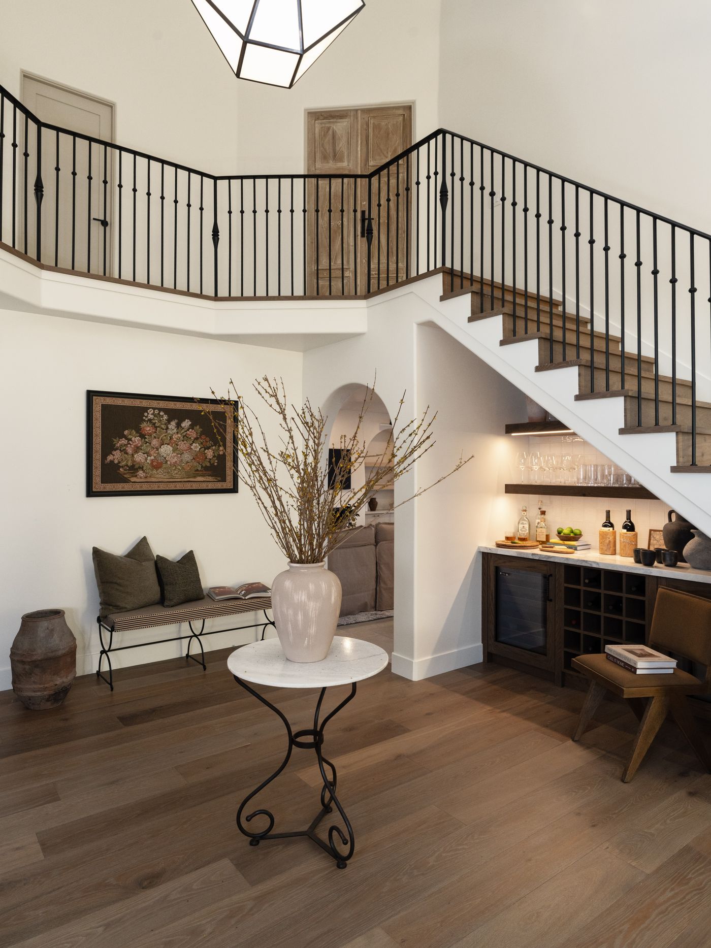 A warm oak stairway with a slender iron railing rising through a light-filled family home