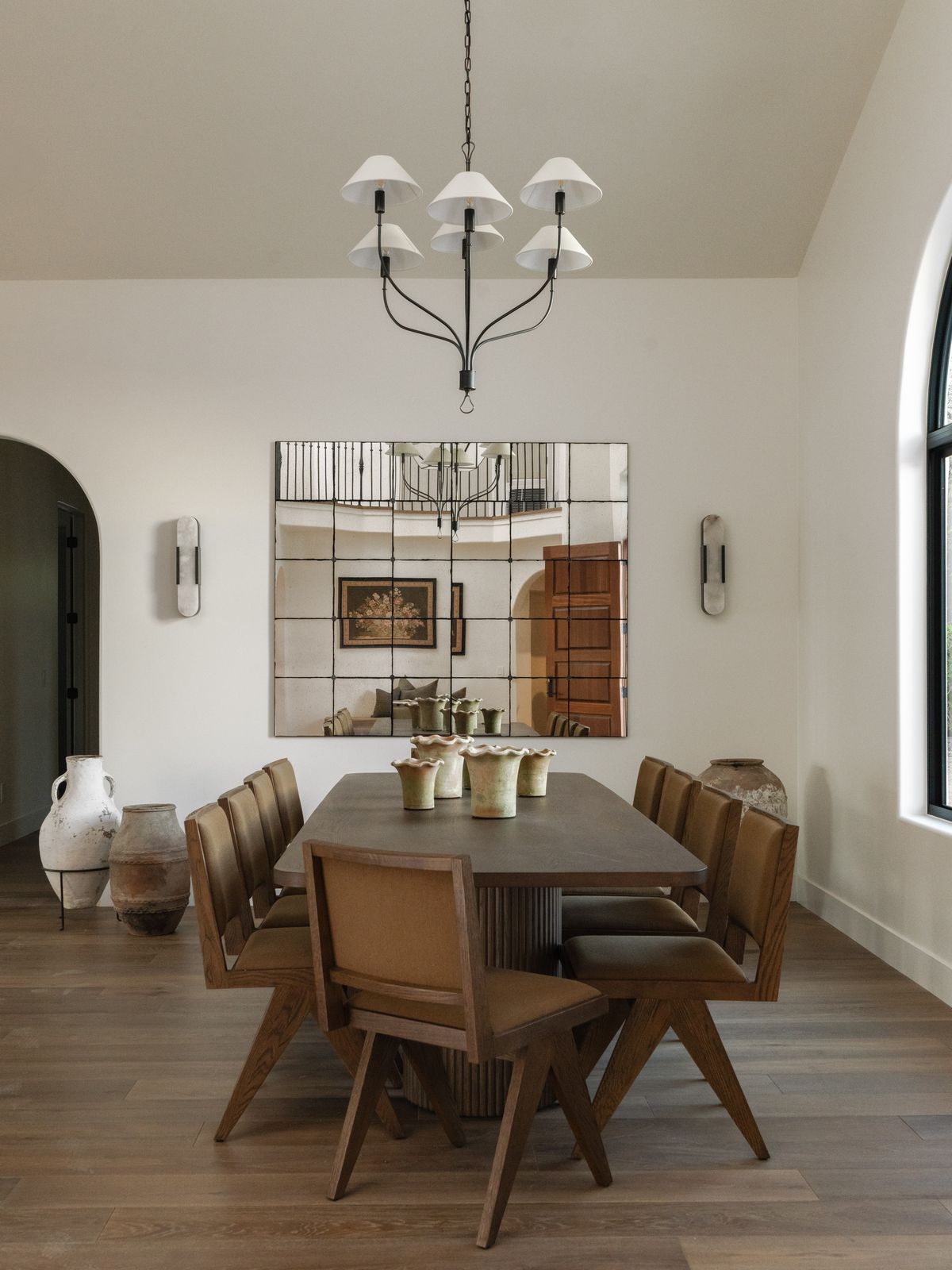 A long family dining table set beneath a quiet chandelier in a warm, light-filled home