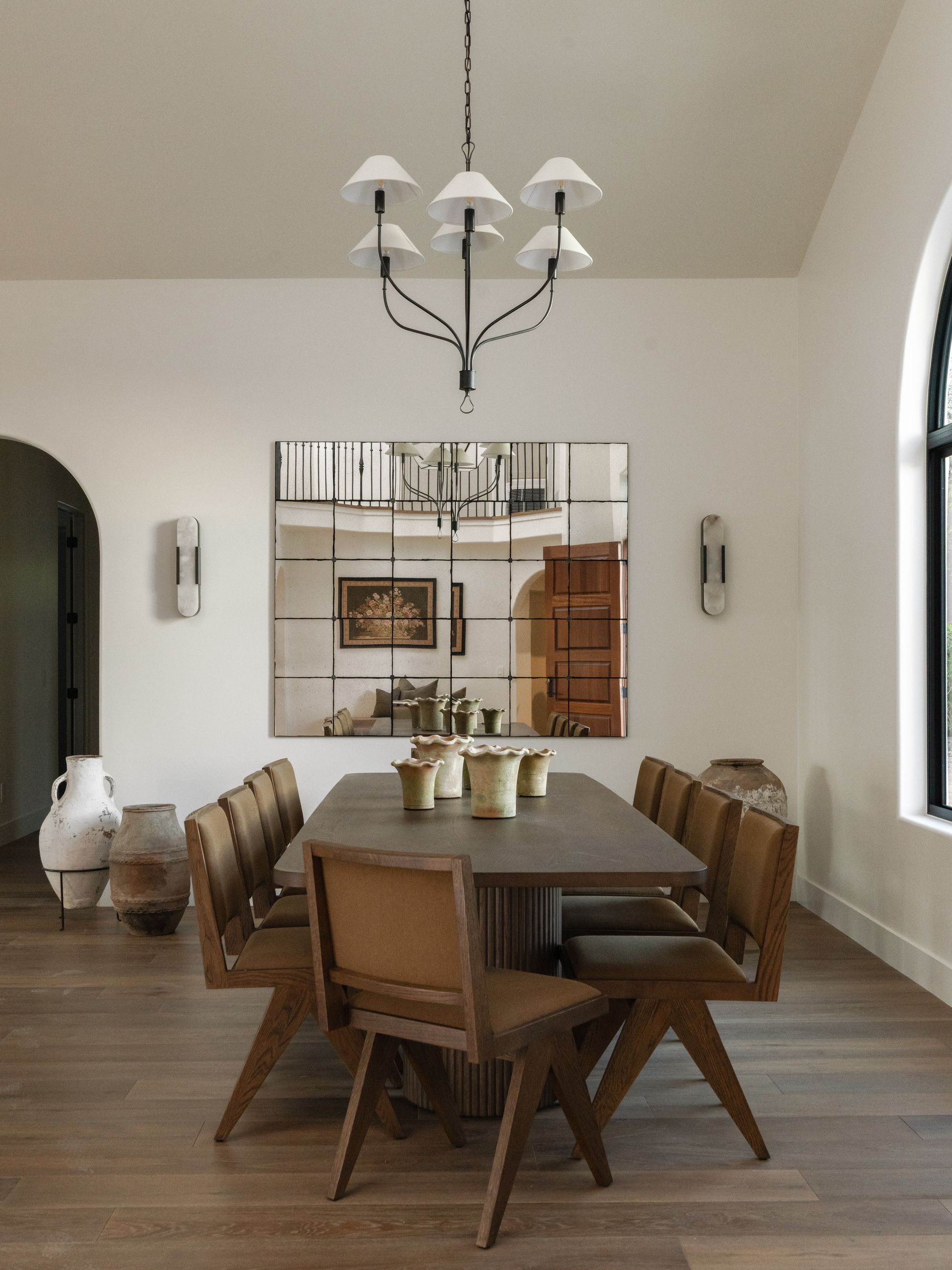 A long family dining table set beneath a quiet chandelier in a warm, light-filled home